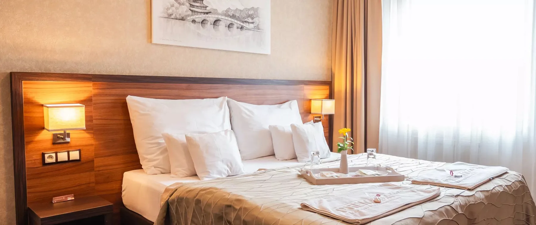 Habitación de hotel con cama doble, cabecero de madera y almohadas blancas.