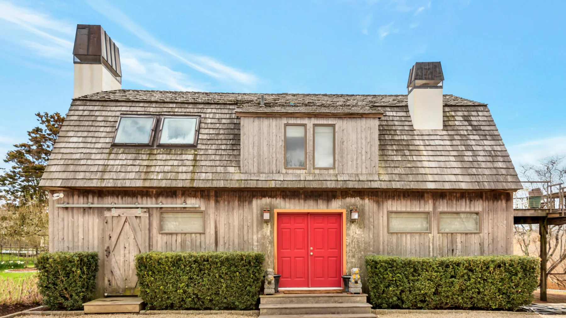 A rustic wooden building with a red front door and dormer windows.