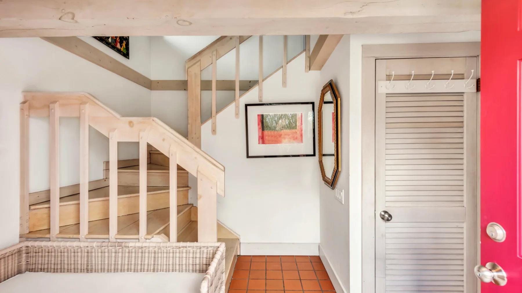 An interior stairway with wooden railings, tiled flooring, and a louvered door.