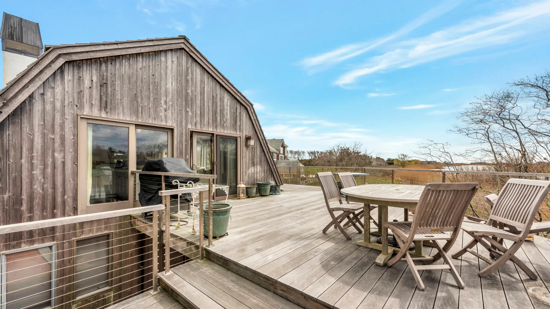 An outdoor deck beside a wooden building, with a dining table and seating.