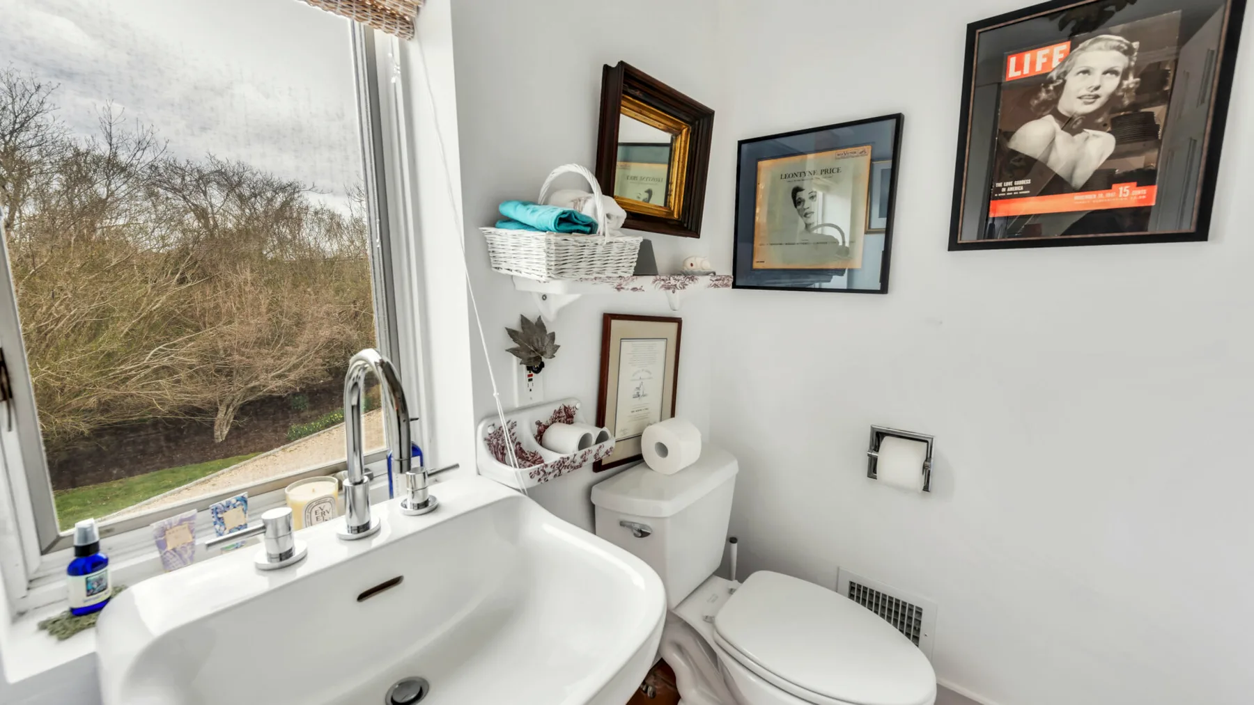 A bathroom with a bathtub, toilet, and large window overlooking trees.