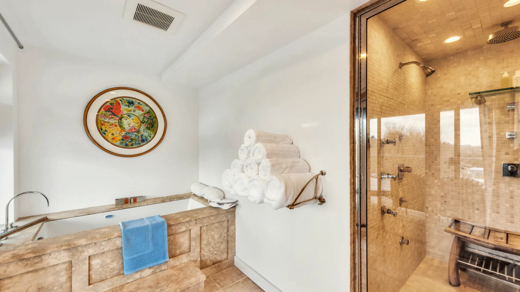 A bathroom with a stone vanity and an adjoining glass-enclosed shower.