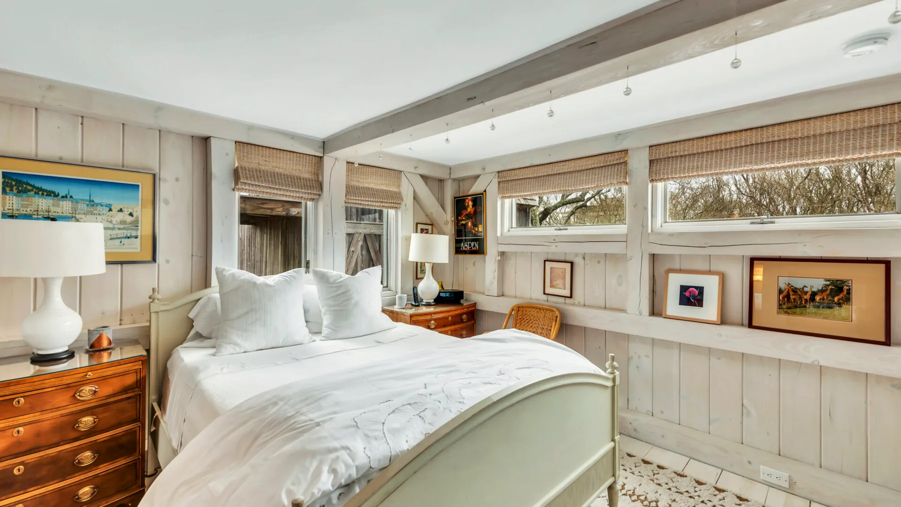 A bright bedroom with a bed beneath wide windows.