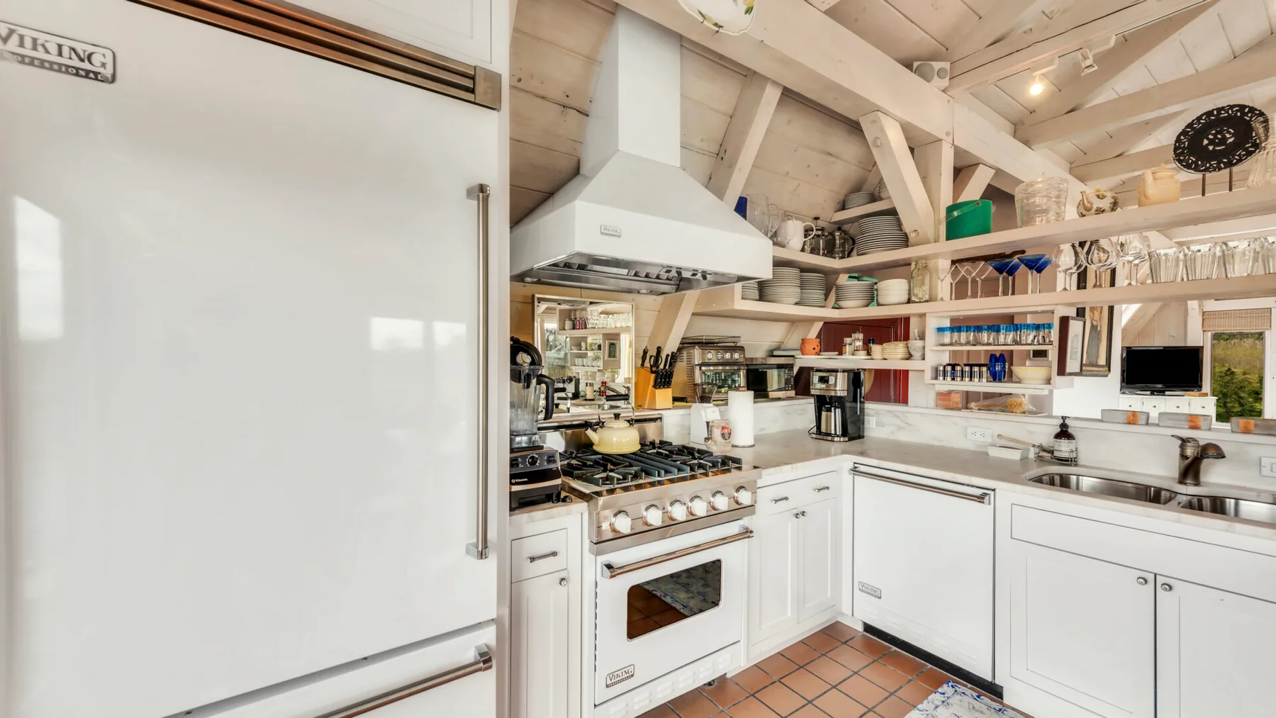 A bright kitchen with white cabinetry, a cooking range, and open shelves.