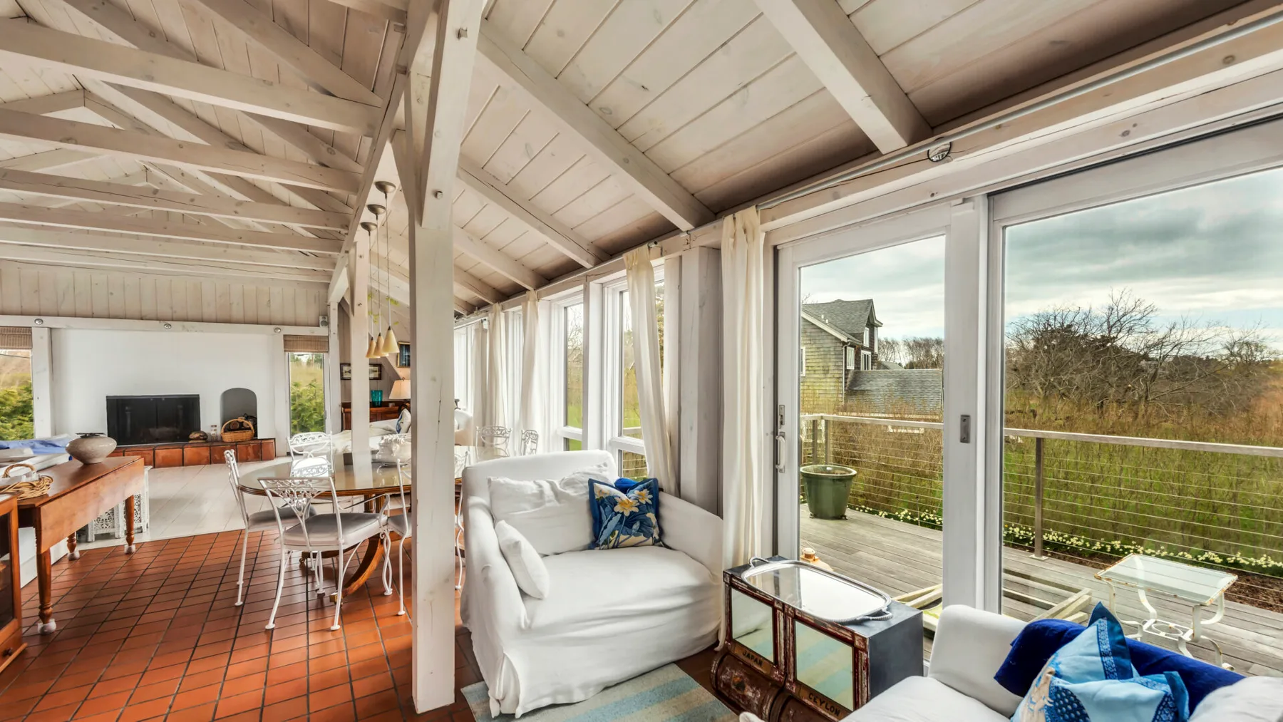 A bright living and dining area has white seating beside large glass doors.