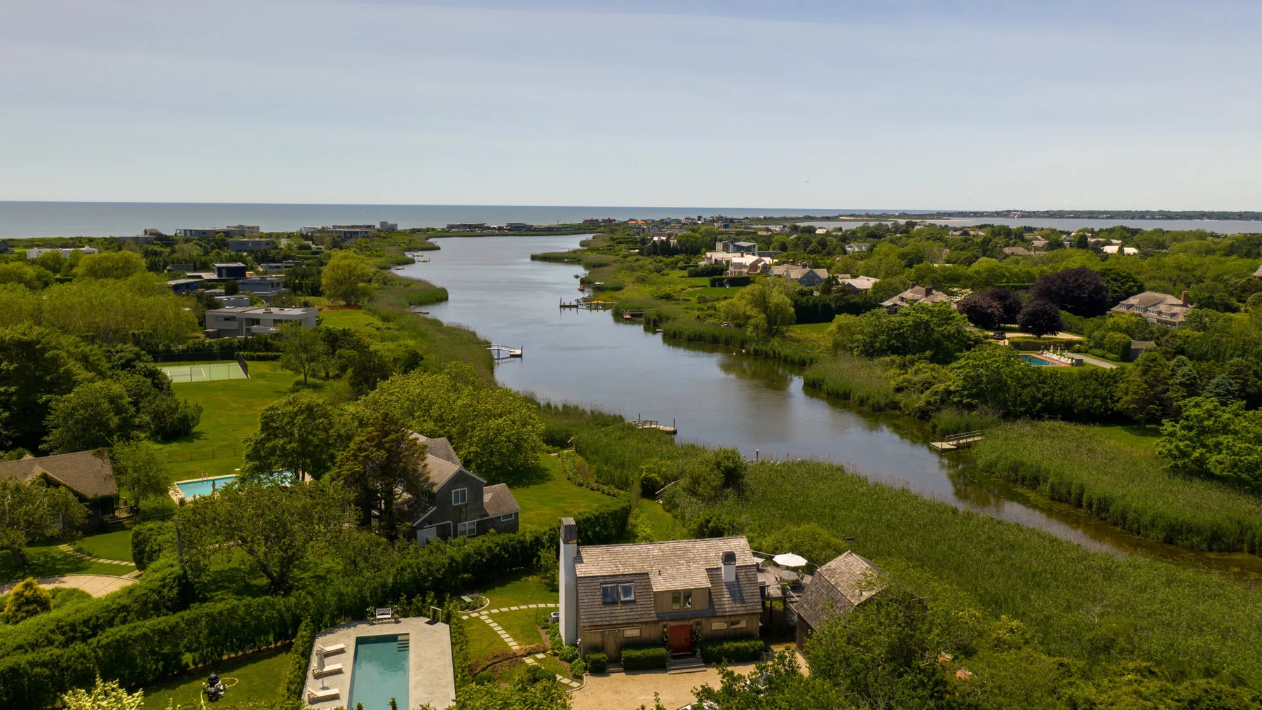 Vista aérea de casas y vegetación junto a un curso de agua sinuoso.