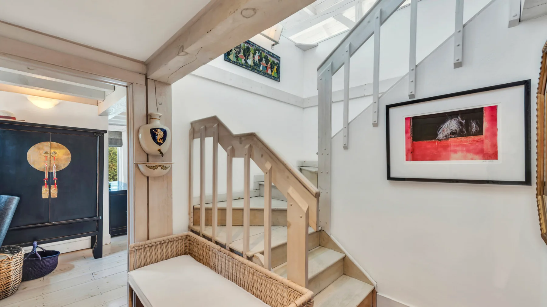 An interior staircase with pale wooden railings and framed artwork on the wall.