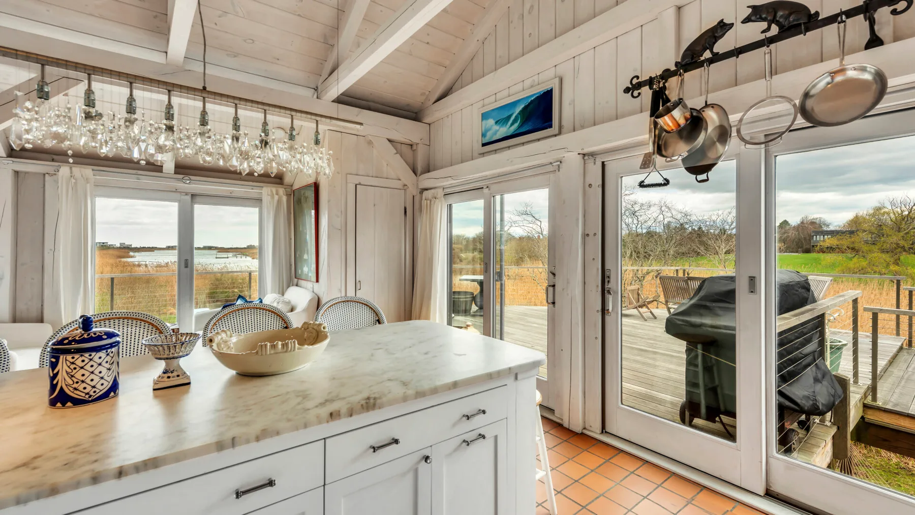 A bright kitchen with a large island and glass doors opening onto a deck.