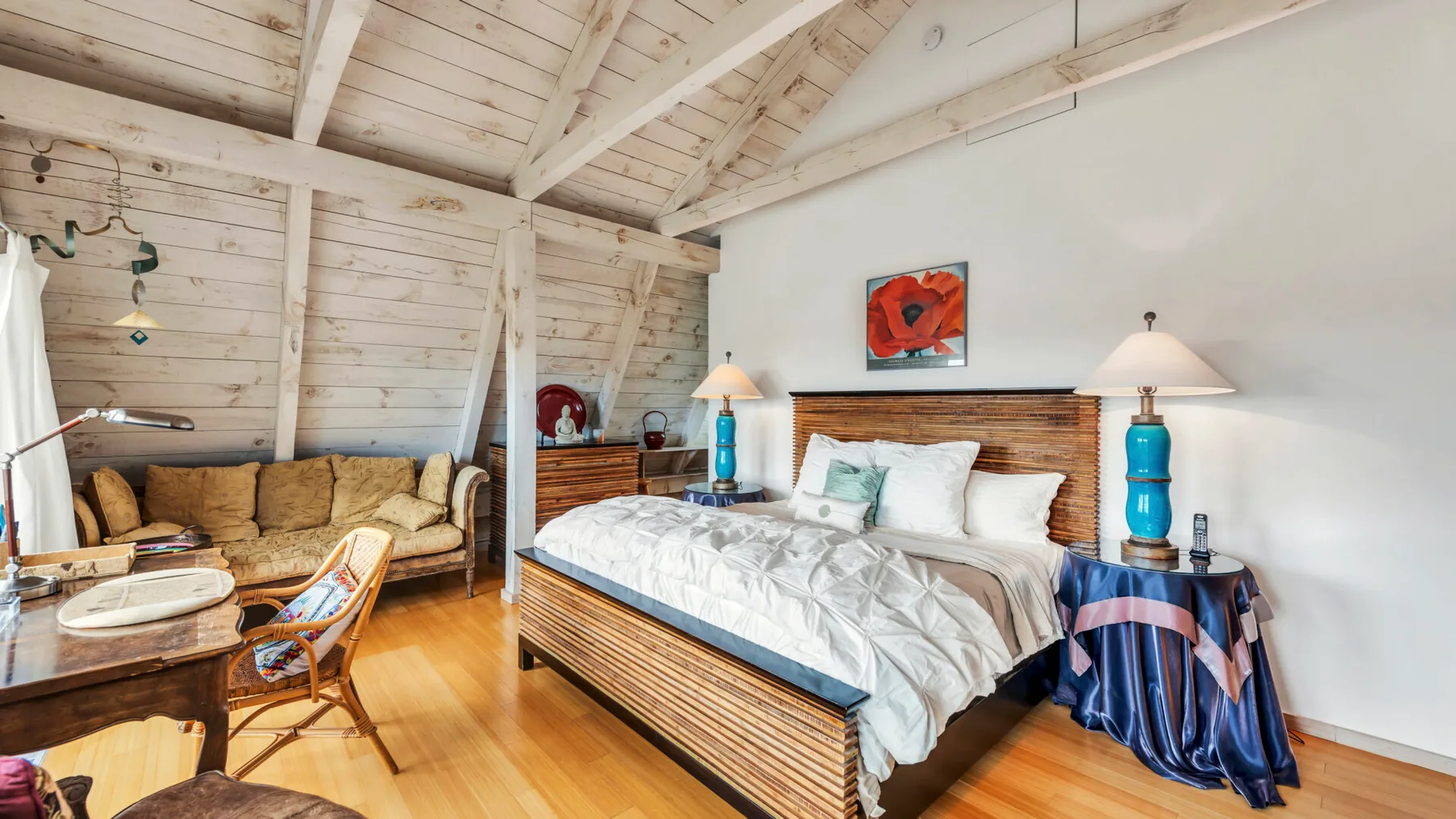 A bedroom with a large bed, bedside lamps, and a seating area.
