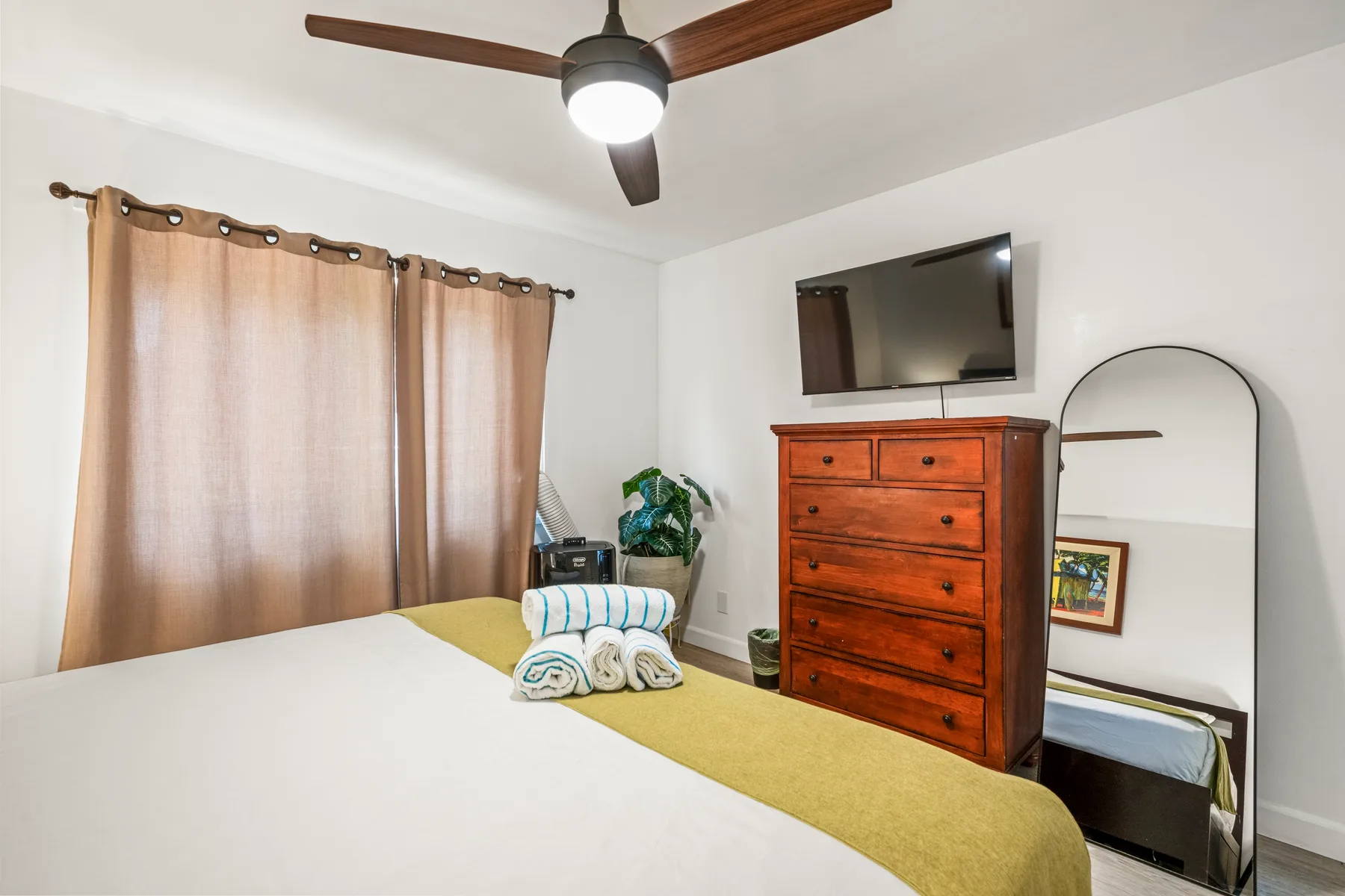 A bedroom with a bed, dresser, and wall-mounted television.