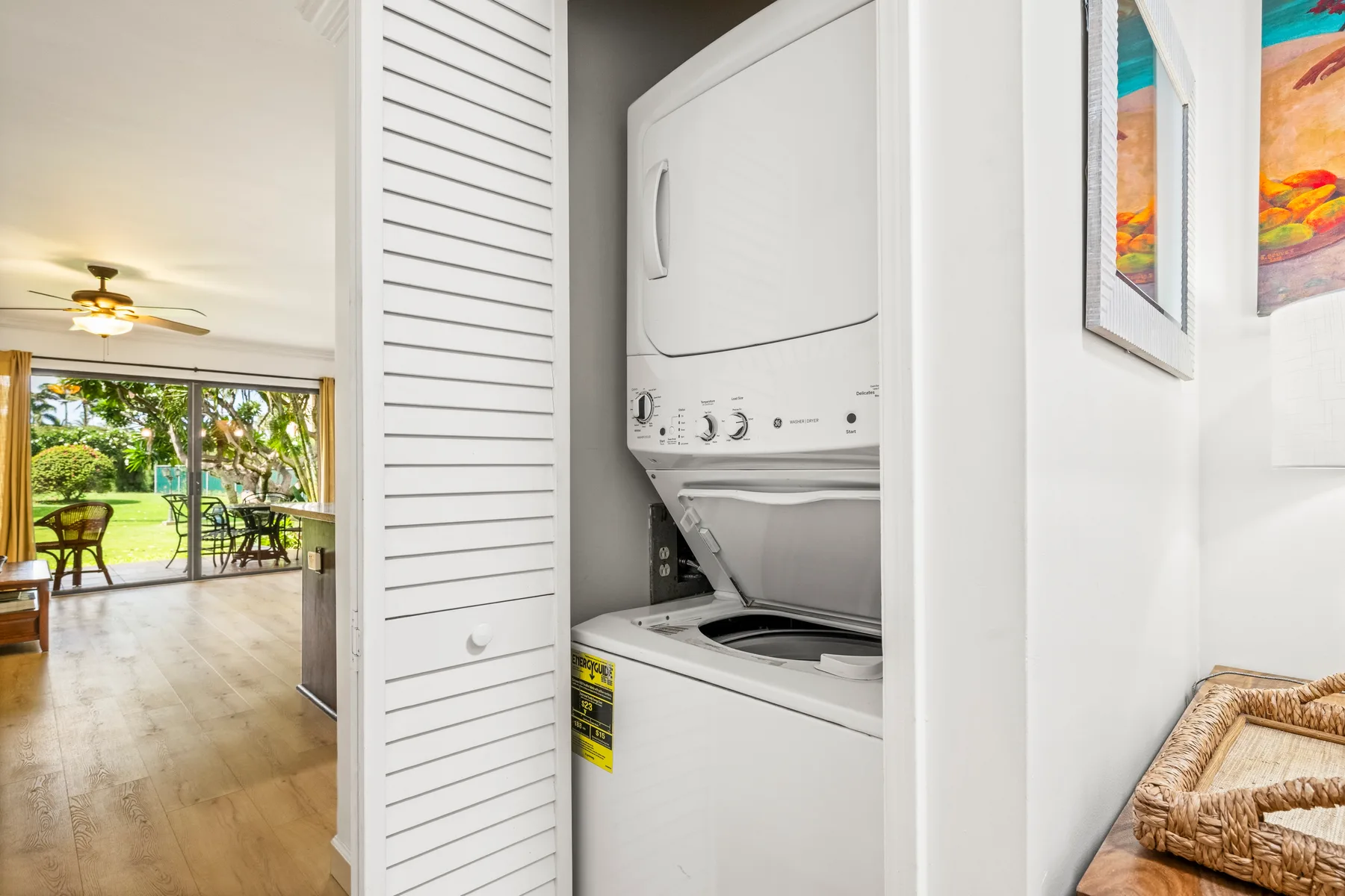 A laundry area with a stacked washer and dryer beside a bright living space.