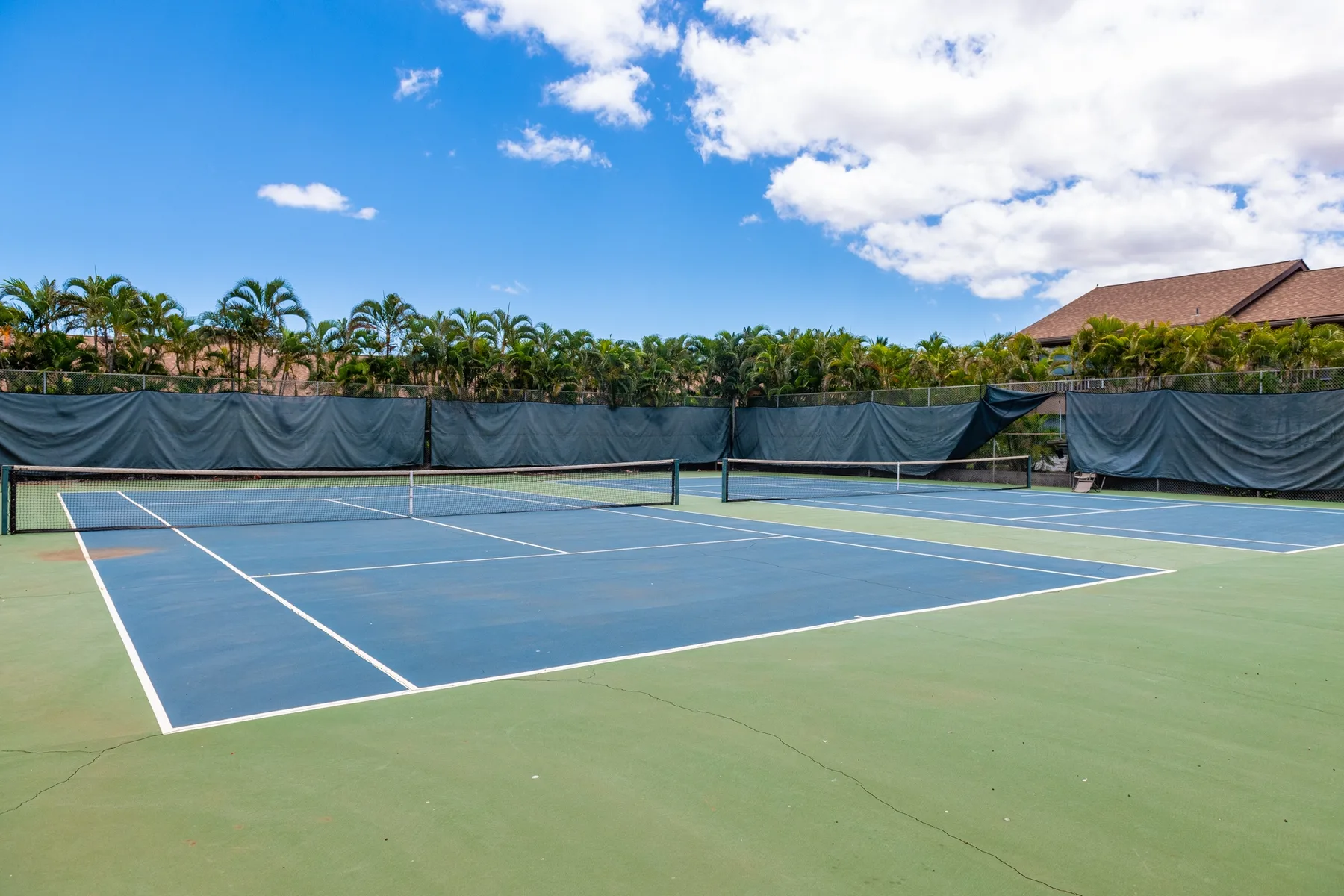 An outdoor tennis court with a net and green surrounding surface.