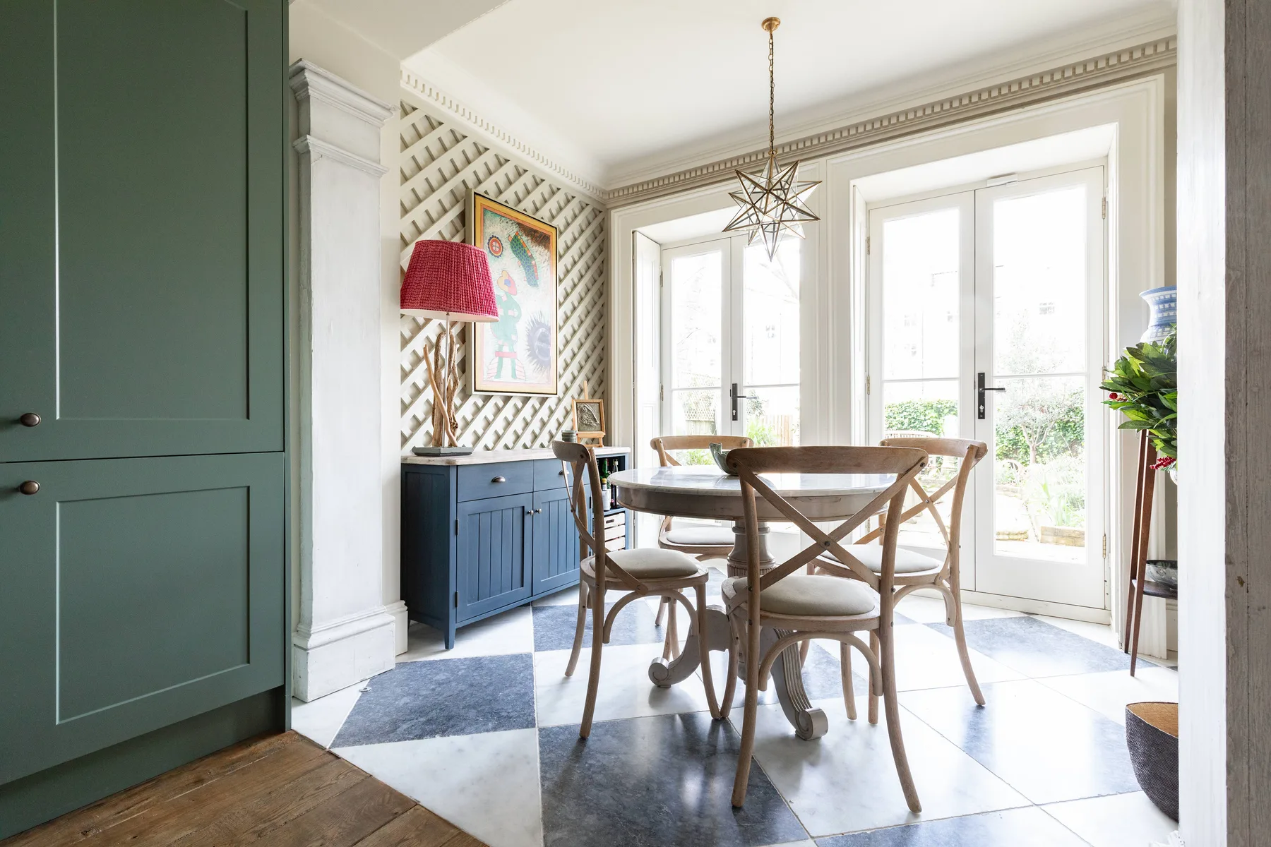 Un comedor luminoso con una mesa de madera y grandes puertas acristaladas.
