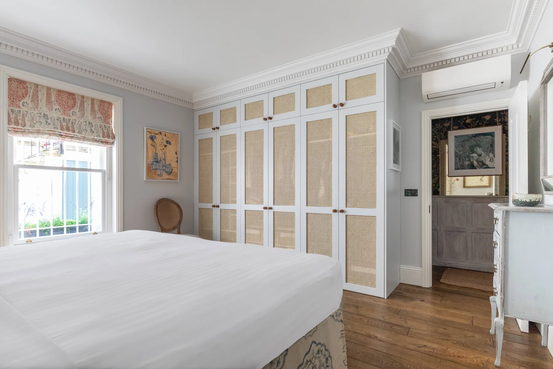 Un dormitorio luminoso con una cama grande, armarios empotrados y una ventana.