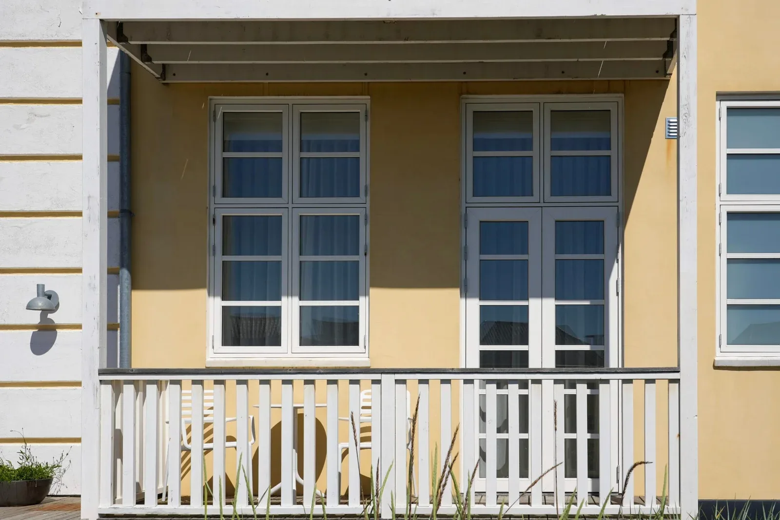 Fachada amarilla de hotel con balcón blanco y puertas