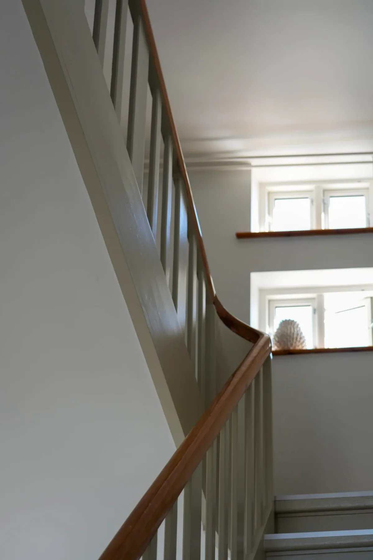 Escalera luminosa con pasamanos de madera y ventanas
