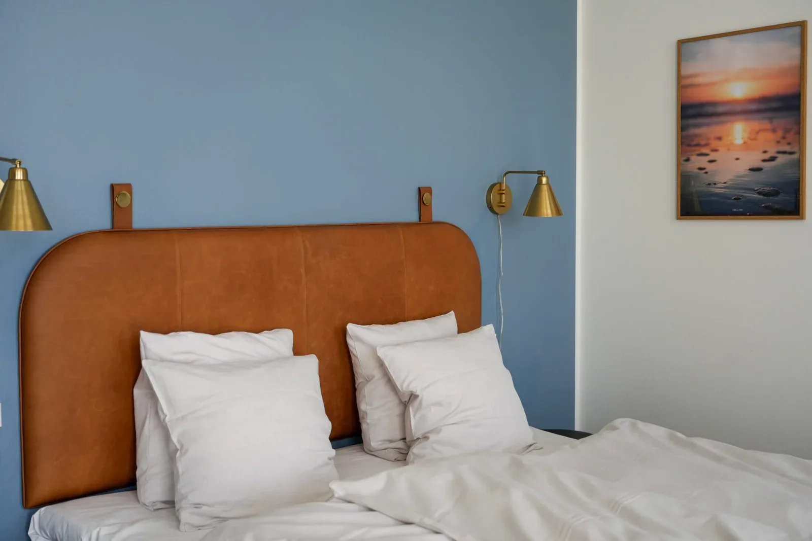 Bed with a brown leather headboard and blue wall