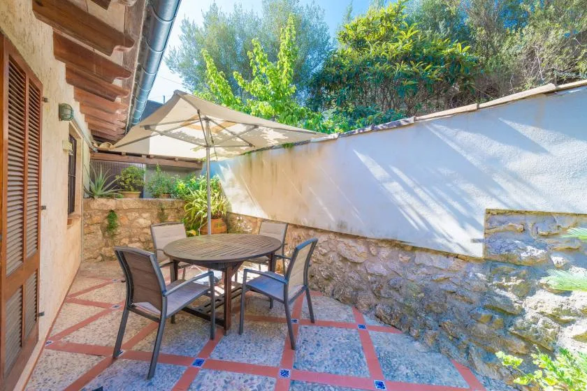 An outdoor patio with a table and seating beneath a sun umbrella.