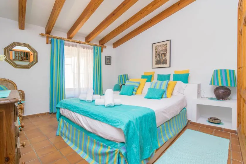 A bedroom with a large bed dressed in turquoise and striped bedding.