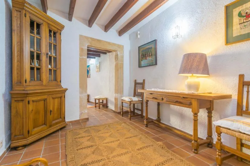 A warmly lit dining room with a wooden table, chairs, and a tall cabinet.