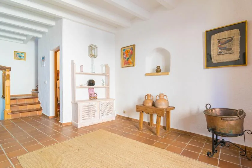 A bright interior room with terracotta floor tiles and a display cabinet.