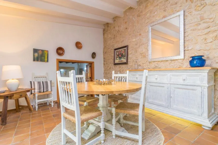A dining area with a wooden table and chairs beside a stone wall.