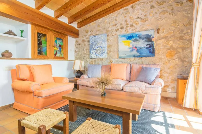 A living room with cushioned seating, a wooden coffee table, and exposed ceiling beams.
