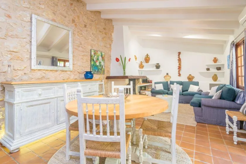 A dining area opens into a living room with teal seating and a wooden table.