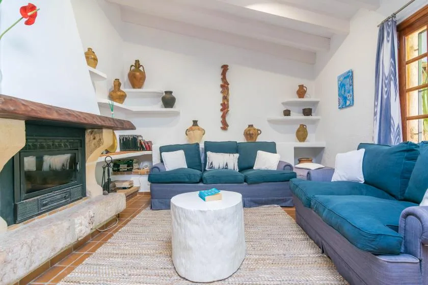 A living room with blue seating, a fireplace, and a low round table.