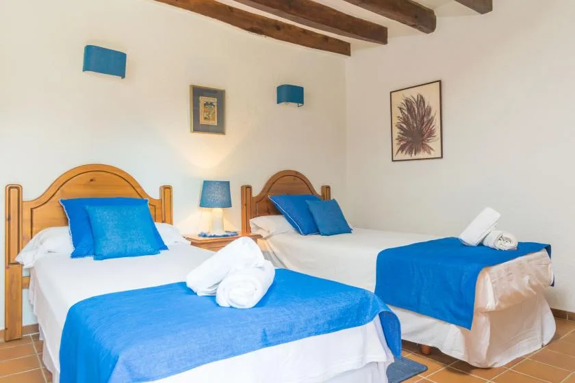 A bedroom with two beds dressed in white and bright blue linens.