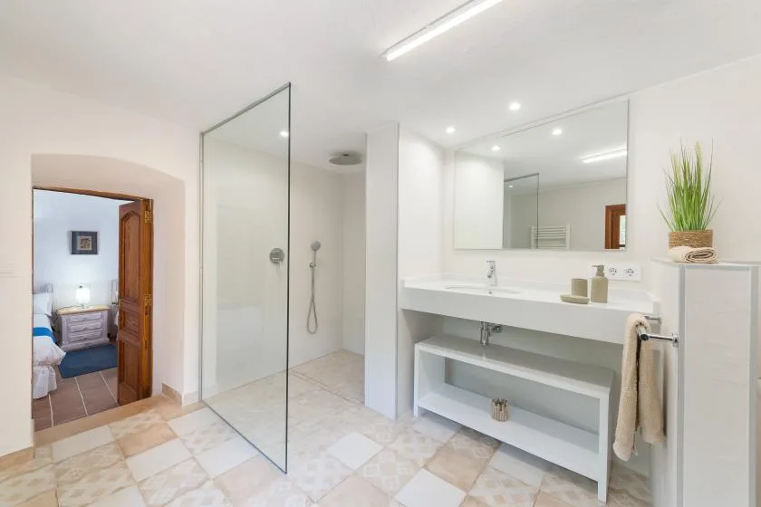 A bright bathroom with a glass shower and a long sink counter.