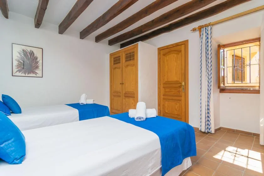 A bedroom with two beds dressed in white linens and blue covers.