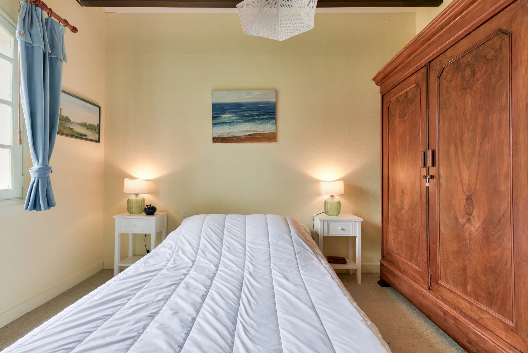 A bedroom with a bed, bedside tables, and a large wooden wardrobe.