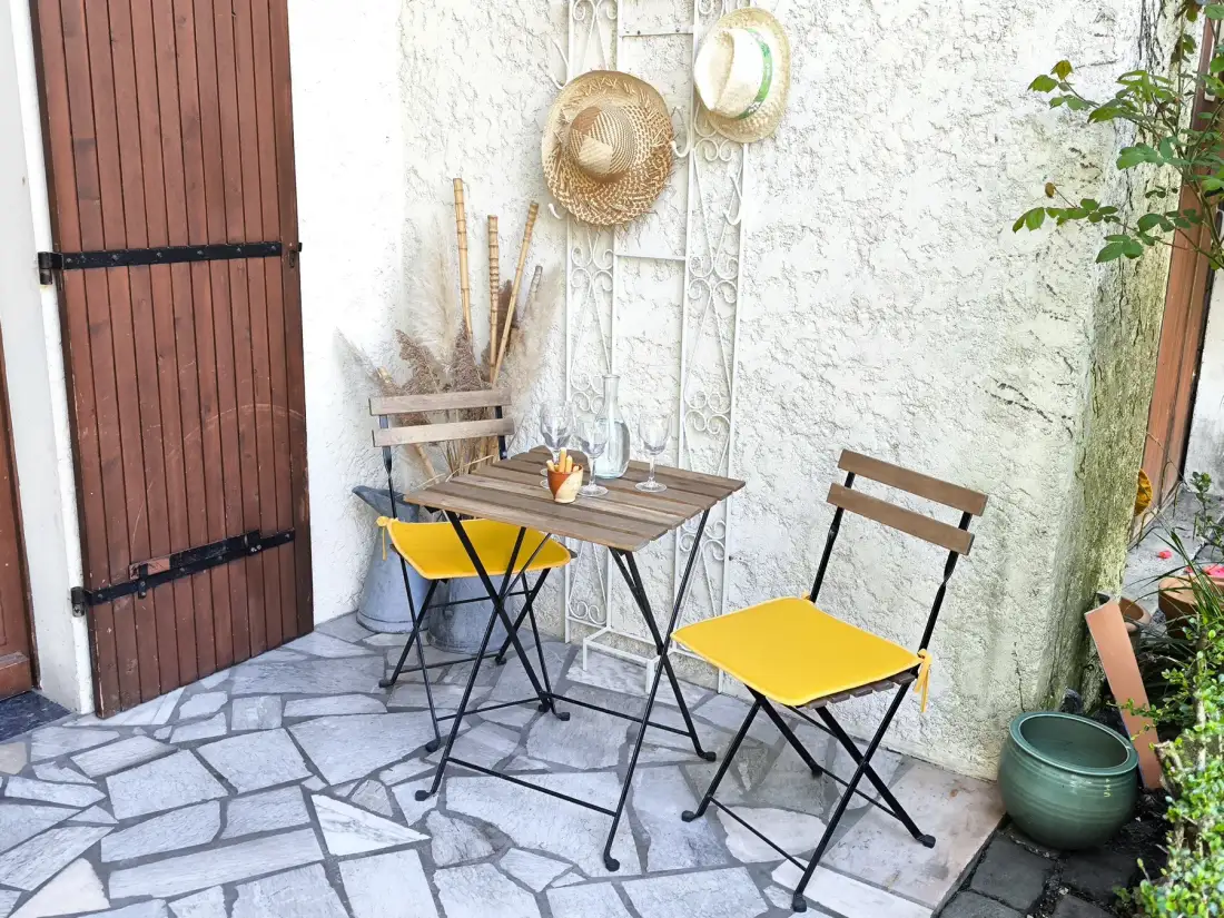 A small outdoor dining area with a table and folding chairs.
