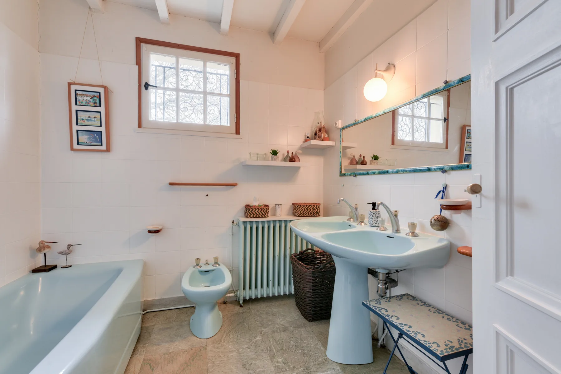 A bright bathroom with a bathtub, sink, and large wall mirror.