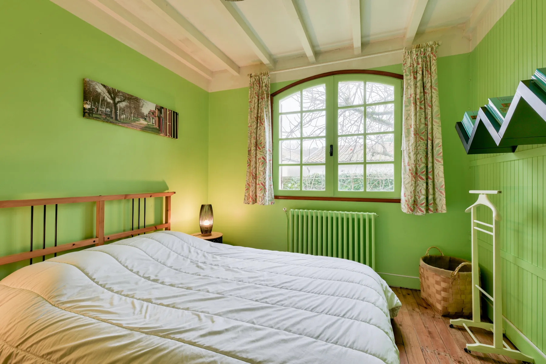 A bedroom with a bed, green walls, and a large window.