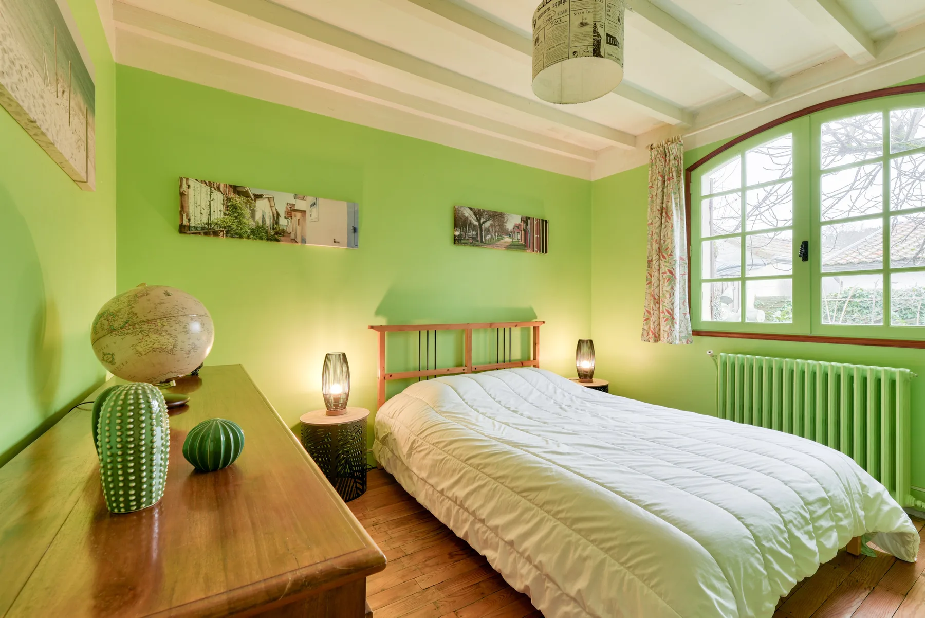 A bedroom with a bed beside a large window.