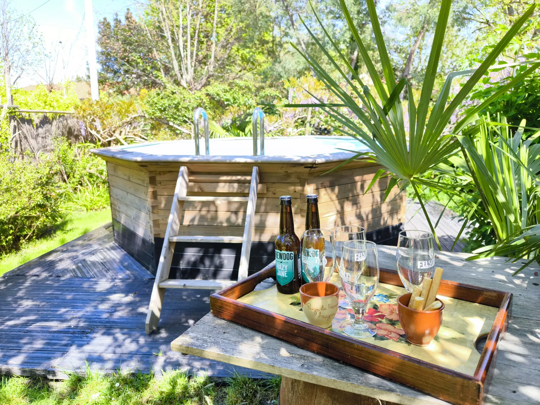 Outdoor patio with a raised hot tub and a drinks tray on a table.