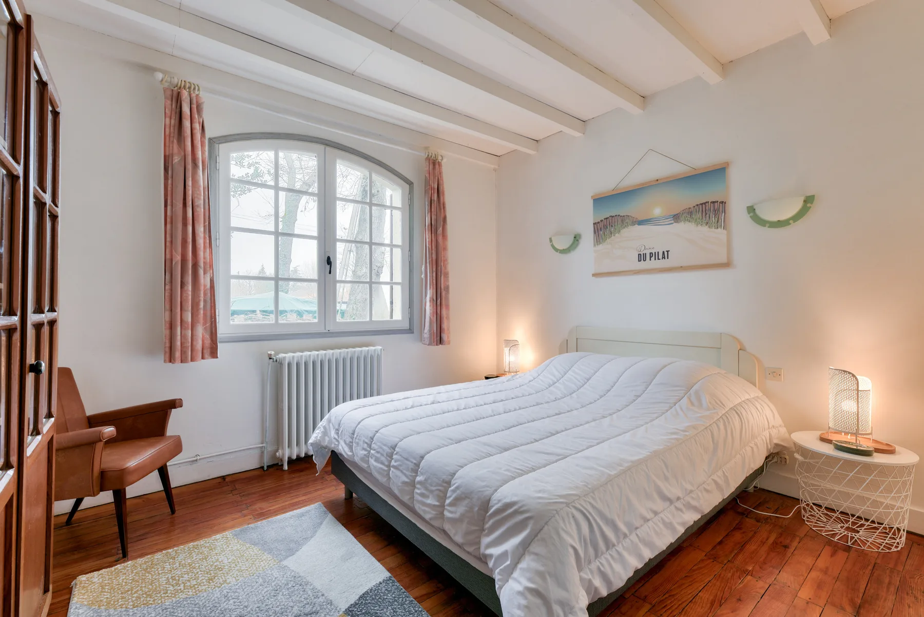 A bedroom with a bed beneath a large window.