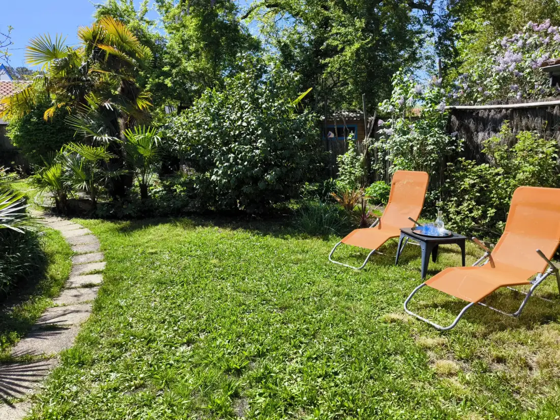 A garden seating area with orange loungers beside a leafy path.