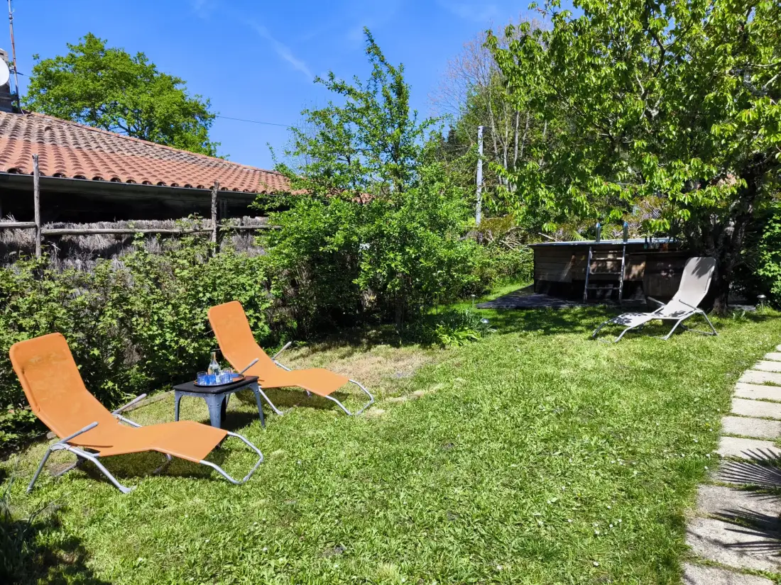 A grassy garden with reclining chairs and a paved path.