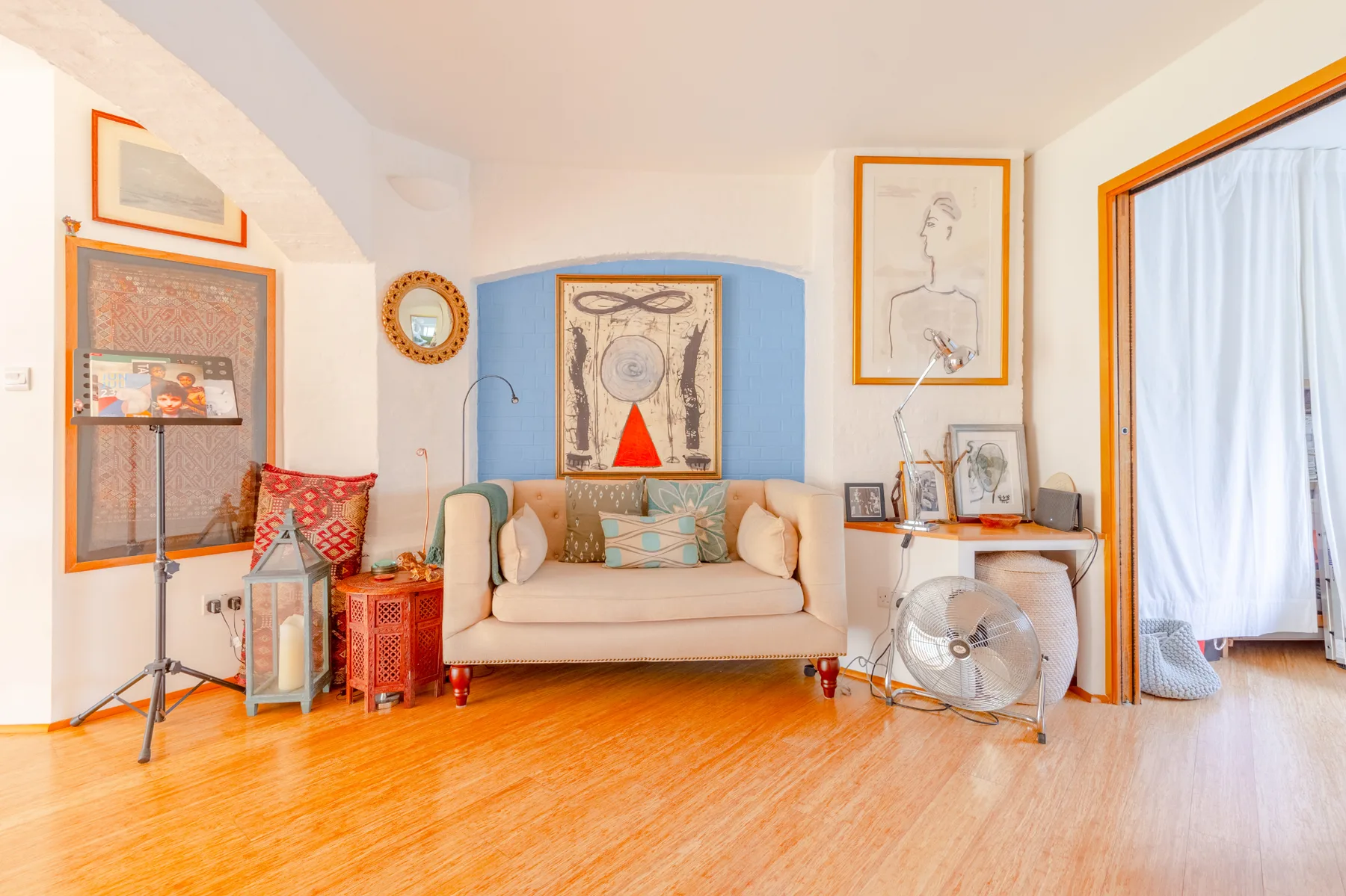 A bright living room with a loveseat and framed artwork.
