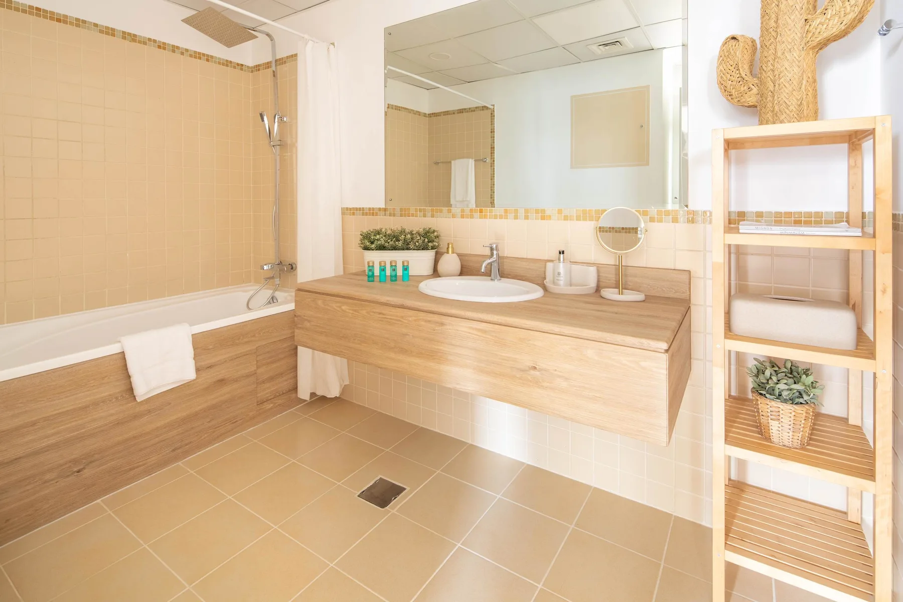 Un baño con azulejos, bañera, ducha y lavabo bajo un espejo grande.