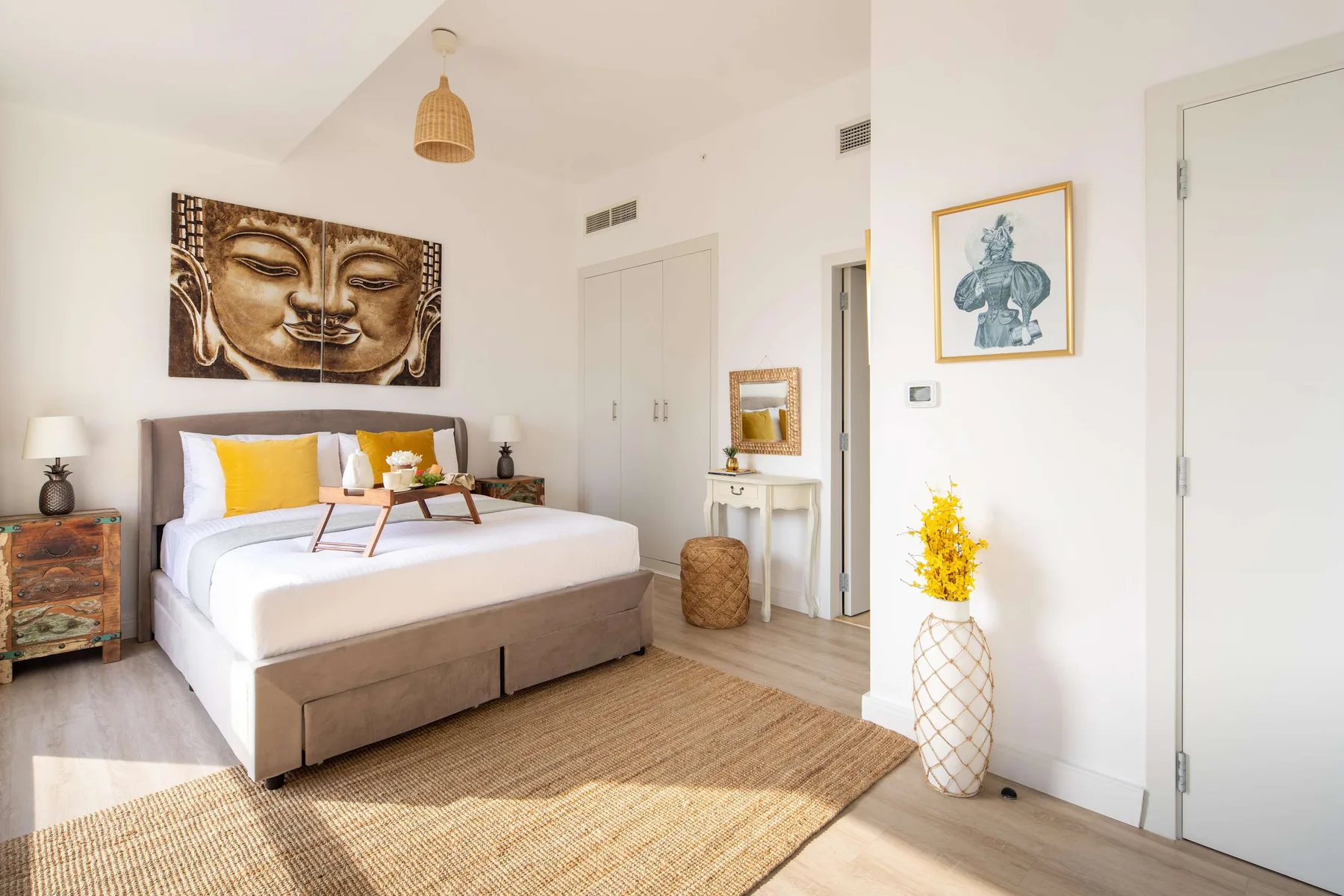 Un dormitorio luminoso con una cama grande, almohadas de colores y una alfombra tejida.