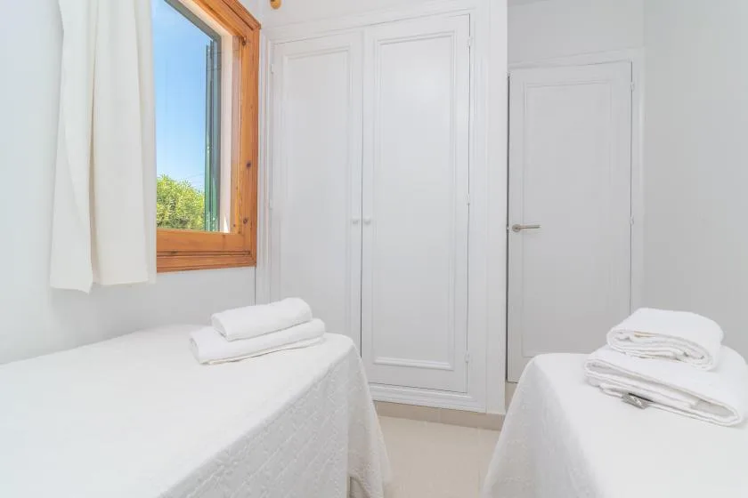 A bright bedroom with two beds and a window.