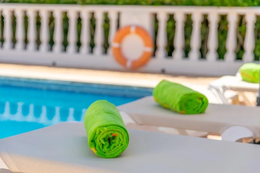 Poolside seating with bright green towels beside the water.