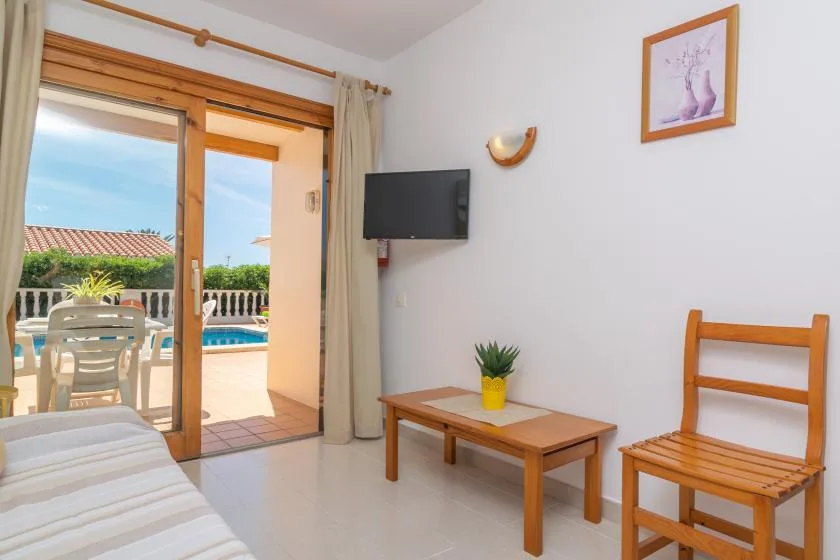 A bright room opens onto a patio with a swimming pool.