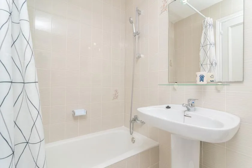 A tiled bathroom with a bathtub, shower, and wide washbasin.