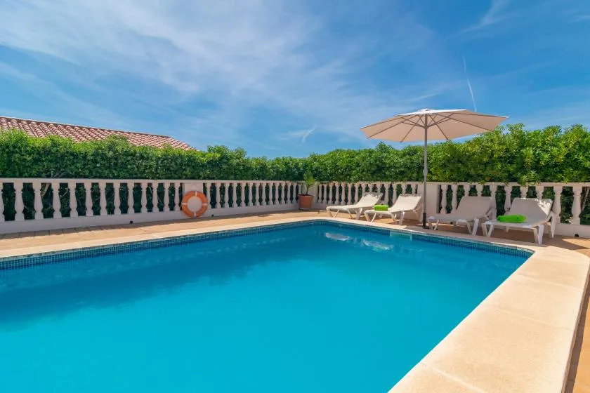 An outdoor swimming pool with lounge seating and an umbrella.