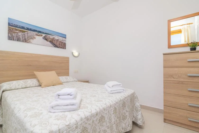 A bedroom with a neatly made bed and folded towels.